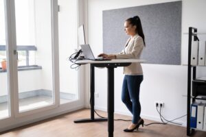 אישה עובדת בעמידה בשולחן מתכוונן.